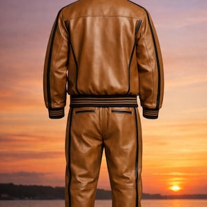 Pu&ograve; includere: Un completo giacca e pantaloni in pelle marrone. La giacca presenta strisce nere sulle maniche e un colletto e cintura a righe nere e marroni. I pantaloni hanno strisce nere sui lati. Il completo &egrave; mostrato su uno sfondo di tramonto.