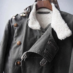 May include: A dark gray jacket featuring a white faux shearling collar and lining. The jacket includes brown circular buttons, toggle-style closures with green cord accents, and a double-breasted front design with a structured collar and lapels.
