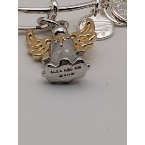 Pode incluir: Uma pulseira de fio expans&iacute;vel em tom prateado com um pingente de anjo bicolor, apresentando asas em tom dourado e corpo em tom prateado. A base do pingente de anjo est&aacute; gravada com o texto ALEX AND ANI e um s&iacute;mbolo de copyright.