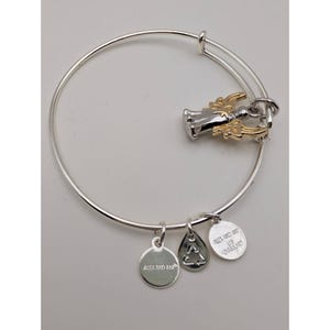 Pode incluir: Uma pulseira de fio expans&iacute;vel em tom prateado com um pingente de anjo bicolor com asas em tom dourado. Tr&ecirc;s pequenos pingentes circulares e em forma de gota pendem do fio, cada um gravado com a marca Alex and Ani e um s&iacute;mbolo de reciclagem.
