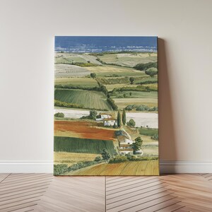 May include: A canvas print of a landscape painting showing rolling hills and fields in shades of green, brown, and orange. Small white buildings with red roofs are scattered throughout the scene. The sky is a light blue.