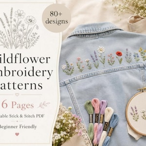 Puede incluir: Chaqueta vaquera azul claro con bordados de flores silvestres. La imagen también muestra hilos de bordar de varios colores, un bastidor de bordado de madera con un diseño floral y un folleto que dice "Wildflower Embroidery Patterns".