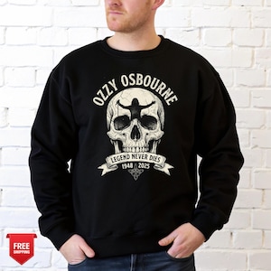 May include: Black sweatshirt featuring a skull graphic with the text "OZZY OSBOURNE" above it. Below the skull is a banner that reads "LEGEND NEVER DIES 1948 2025". The graphic is in white and black.