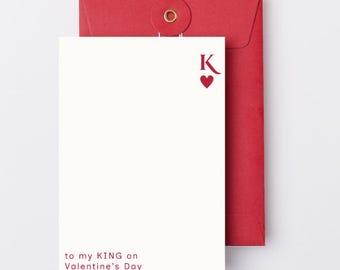 May include: A white card with the text "to my KING on Valentine's Day" in red, along with a red heart and the letter "K". The card is paired with a red envelope.