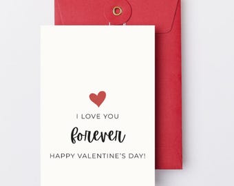 May include: A white Valentine's Day card with a red heart and the words "I LOVE YOU forever HAPPY VALENTINE'S DAY!" is placed in front of a red envelope.
