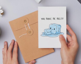 May include: A white greeting card with the text "YOU MAKE ME MELT!!" and an illustration of two cartoon ice cubes melting. The card is held in a person's hands, next to a brown envelope.