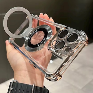 Könnte beinhalten: Transparente Handyhülle mit silbernem Rahmen und Akzenten. Die Hülle verfügt über einen kreisförmigen Magnetring und einen Kameraschutz. Der Text "colnel" ist auf dem Ring sichtbar. Entwickelt, um die Kamera und das Gehäuse des Telefons zu schützen.