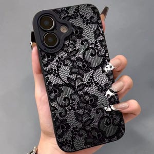 Könnte beinhalten: Schwarze und graue Handyhülle mit Spitzenmuster. Die Hülle hat einen Kameraschutz. Das Muster der Hülle ist floral.