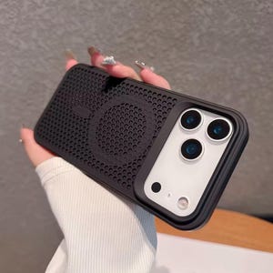 Peut inclure: Coque de téléphone noire avec un design perforé et un module caméra. L'étui a une finition mate et un motif circulaire au dos. Le module caméra comporte trois lentilles et un flash.