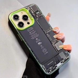 Peut inclure: Une coque de téléphone transparente avec un cadre vert et vert citron, montrant les composants internes d'un téléphone. La coque porte l'inscription "SO COOL" et une étiquette de batterie. La coque est conçue pour protéger le téléphone tout en affichant ses composants.