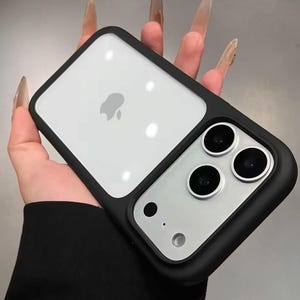 May include: Black and clear phone case with a black border. The case has a clear section with the Apple logo and a section with three camera lenses. The phone case is designed to protect the phone.