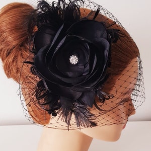 May include: Black bridal hair comb with a large black satin flower, black feathers, and a black birdcage veil.