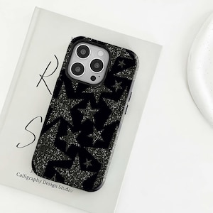 Könnte beinhalten: Schwarze Handyhülle mit einem glitzernden Sternmuster. Die Hülle hat eine glänzende Oberfläche und einen Kameraausschnitt. Der Text "Calligraphy Design Studio" ist auf dem Buch darunter gedruckt.