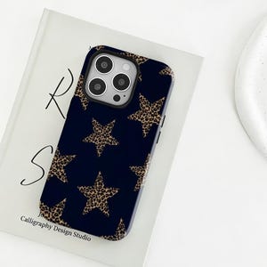 May include: A navy blue phone case featuring a pattern of leopard print stars. The case has a glossy finish and a camera cutout. The text "Calligraphy Design Studio" is visible at the bottom of the case.