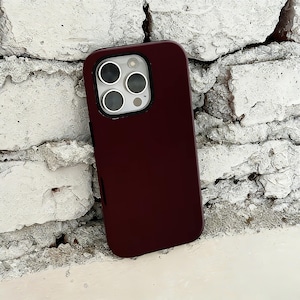 Könnte beinhalten: Eine weinrote Handyhülle mit glänzendem Finish. Die Hülle hat eine rechteckige Form mit abgerundeten Ecken und einem Kameraausschnitt. Die Handyhülle ist zum Schutz eines Smartphones konzipiert.