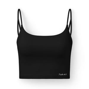 May include: A solid black cropped camisole top featuring thin spaghetti straps and a scoop neckline. The garment has the text Psalm 46:5 printed in a small white script font on the lower right side of the front panel of the black fabric.