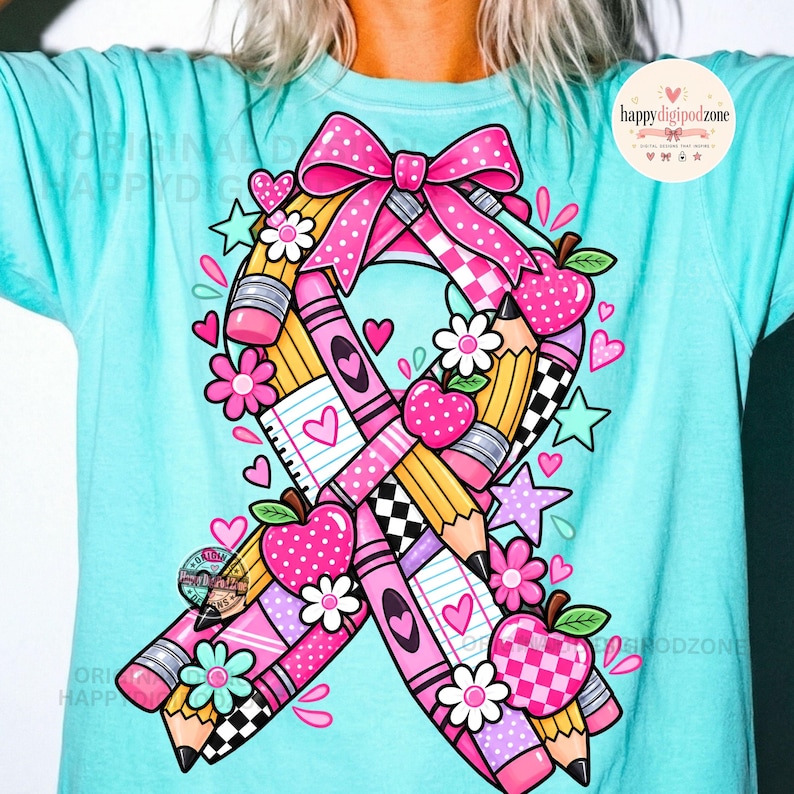 May include: A light turquoise t-shirt featuring a large awareness ribbon graphic composed of yellow pencils, pink crayons, lined paper, and red apples. The design includes a pink polka-dot bow, small flowers, and stars. Text reads "happydigipodzone".
