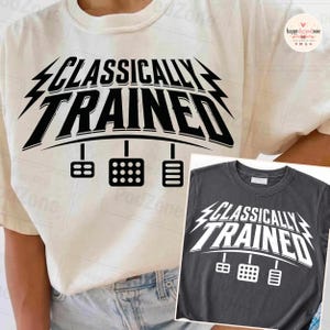 May include: A cream-colored t-shirt featuring the black text "CLASSICALLY TRAINED" above a graphic of three car pedals. An inset shows a dark gray t-shirt with the same white text and pedal graphic, highlighting the design on two different shirt colors.