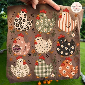 May include: A brown t-shirt featuring a repeating pattern of nine stylized chickens with various prints including leopard spots, floral motifs, stripes, polka dots, and gingham checks, interspersed with small hearts, stars, and flowers.