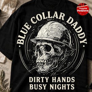 May include: Black t-shirt with a white graphic of a skull wearing a hard hat. The text "BLUE COLLAR DADDY" is arched around the skull, with "DIRTY HANDS BUSY NIGHTS" below. The design is distressed.