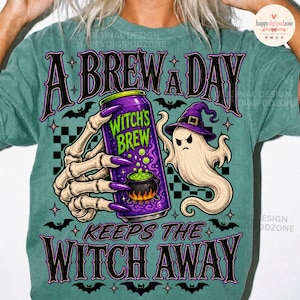 May include: A mineral-washed teal t-shirt featuring a graphic of a skeleton hand holding a purple can labeled Witch's Brew, a ghost in a purple hat, and bats. The text reads A BREW A DAY KEEPS THE WITCH AWAY in a stylized black font with purple outlines.