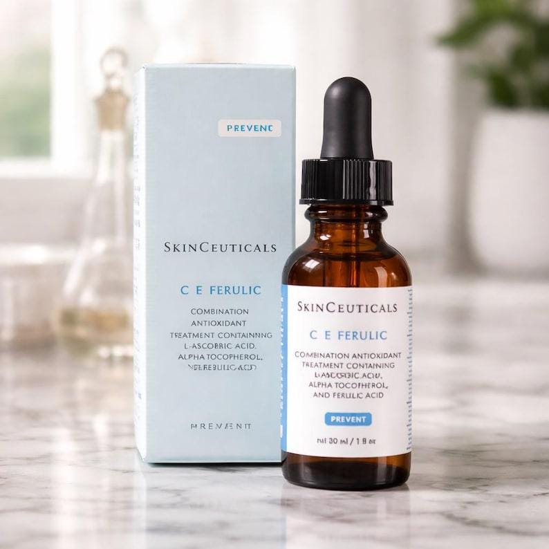 May include: A SkinCeuticals C E Ferulic combination antioxidant treatment in a brown glass dropper bottle with a black cap, accompanied by its light blue cardboard box. The label and box text specify it contains L-ascorbic acid, alpha tocopherol, and ferulic acid, with a net volume of 30 ml / 1 fl oz.