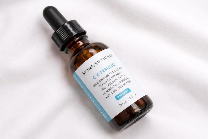 May include: A brown glass dropper bottle of SkinCeuticals C E Ferulic serum with a black dropper cap. The white label features blue text detailing the ingredients including 15% L-ascorbic acid, 1% alpha tocopherol, and 0.5% ferulic acid, totaling 30 ml / 1 fl oz.