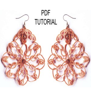 May include: A pair of delicate, intricate earrings made with orange thread. The earrings are shaped like a flower with a small, clear bead in the centre. The earrings are hanging from silver hooks.