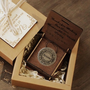 Puede incluir: Una moneda de decisión personalizada en una caja de madera. La moneda es de color plateado con el nombre "Krista" y el texto "Flip to Decide". La caja tiene texto grabado: "Gracias por hacer que nuestras vidas sean memorables y valiosas."