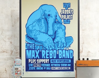 May include: A framed poster featuring a blue elephant-like creature with the text "THE MAX REBO BAND" and "LIVE AT JABBA'S PALACE." The poster includes additional text about the event and is displayed with a vintage robot toy and radio.