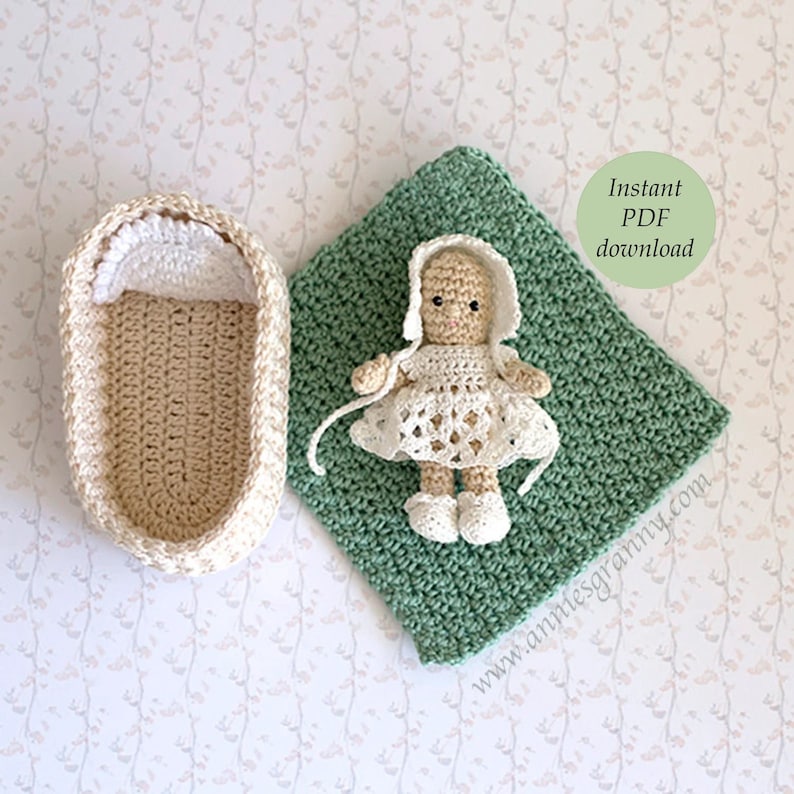 Crochet baby doll lying on a green blanket. A basket with a white crochet pillow.