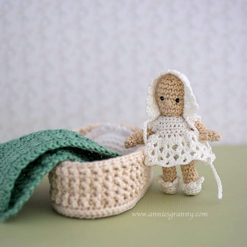 Crochet baby doll with white dress and cap. Basket with a blanket and a pillow.