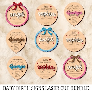May include: A selection of laser-cut wooden baby birth signs. The signs display names like "Angel", "Sophia", and "George", with decorative bows, hearts, and scalloped edges. Each sign includes space for date and time.