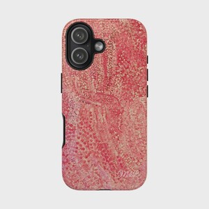 Pode incluir: Uma capa de telefone com um design abstrato rosa e branco. A capa tem uma aparência texturizada com um padrão de pequenos pontos e uma assinatura no canto inferior direito. A capa tem detalhes em preto ao redor da câmera e das laterais.