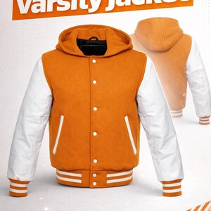 Op de afbeelding: Oranje en witte varsity jas met een capuchon. De jas heeft witte mouwen, een knoopsluiting en gestreepte manchetten en zoom. De tekst "Customized varsity jacket" wordt bovenaan weergegeven.