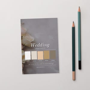 Peut inclure: Une carte de palette de couleurs de mariage avec un motif floral et le mot "Wedding" en écriture élégante. La carte présente une sélection d'échantillons de couleurs neutres et est accompagnée de deux crayons, un vert d'eau et un vert foncé.