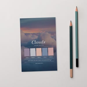 May include: A color palette card titled "Clouds" with a sky and cloud image, featuring a range of pastel colors. Two pencils, one dark green and one teal, are positioned to the right of the card. The card includes hex codes and a website address.