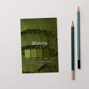Peut inclure: Une carte de palette de couleurs Matcha avec un fond vert texturé et le mot "Matcha" en écriture blanche. La carte affiche cinq nuances de vert avec les codes hexadécimaux correspondants. Deux crayons, un vert d'eau et un vert, sont positionnés à droite.
