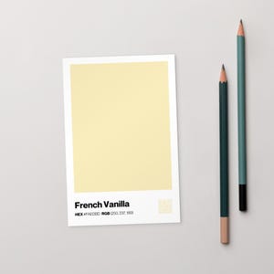 Pode incluir: Um cartão retangular com uma amostra de cor amarelo pálido, rotulada como "French Vanilla". Dois lápis, um verde-azulado e outro verde escuro, estão posicionados à direita. O cartão exibe os códigos de cor HEX e RGB.
