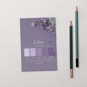 May include: A lilac color palette card with a floral arrangement and two pencils. The card features the word "Lilac" and a series of color swatches. The pencils are green and teal with a wooden tip.