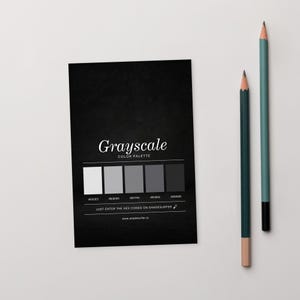 May include: A black card featuring a grayscale colour palette with the text "Grayscale COLOR PALETTE". Two pencils, one teal and one dark green, are placed to the right of the card.
