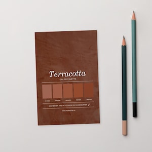 May include: A terracotta colour palette card with the text "Terracotta COLOR PALETTE" and a series of colour swatches. Two pencils, one dark green and one light green, are positioned to the right of the card.