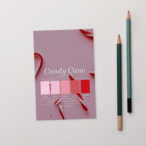 May include: A pink color palette card with the words "Candy Cane" and a color scheme of pink and red hues. Two pencils, one green and one teal, are positioned to the right of the card. Candy canes are scattered around the card.