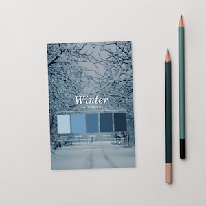 May include: A card featuring a winter colour palette with a snowy forest image and the word "Winter". Five shades of blue are displayed. Two pencils, one green and one teal, are placed to the right of the card.