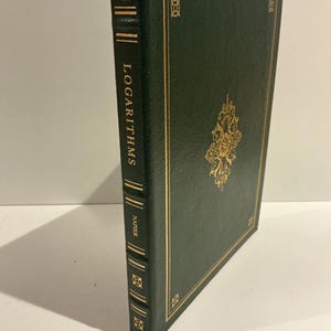 Puede incluir: Un libro de tapa dura verde oscuro titulado "LOGARITHMS" de Napier. La portada y el lomo presentan elementos decorativos y texto dorados. El diseño del libro incluye bordes dorados y un emblema central.