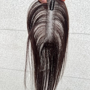 Puede incluir: Una taza de cerámica blanca con asa negra y el texto "But First, Coffee" en negrita negra. La taza se encuentra sobre un fondo borroso, sugiriendo un ambiente acogedor.