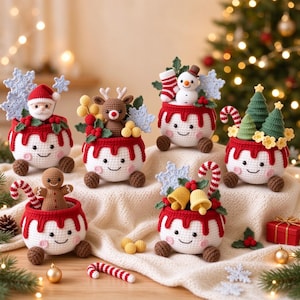May include: A collection of six crocheted Christmas pudding-shaped containers, each with a smiling face, brown feet, and red icing trim. They feature various toppers including a Santa, reindeer, snowman, gingerbread man, bells, and trees.