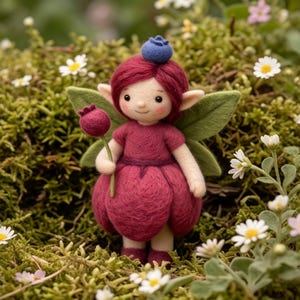 May include: A needle-felted fairy figurine with deep red hair, a matching red petal-shaped skirt, and a dark red top. The figure has pointed ears, green felt wings, and holds a small red berry on a stem. A blue berry sits atop its head.