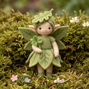 May include: A needle-felted fairy figurine with a pale complexion and rosy cheeks, wearing a green leaf-shaped hat and a skirt made of layered green leaves. The figure has large green leaf wings, pointed ears, and holds a small four-leaf clover.