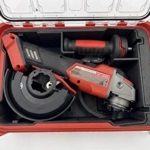May include: A red and black power tool set in a red case. The set includes a grinder, a handle, and a cutting disc. The case has a clear top and black interior compartments. The grinder is red and black with a silver head.